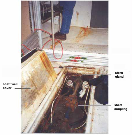 Photo 3 - Part of the fish hold, looking aft, showing the spatial relationship between the foot of the aluminum ladder, stern gland, shaft well cover, and shaft coupling.