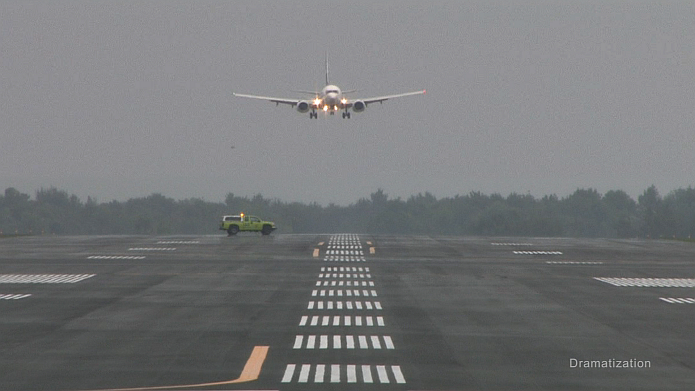 Runway vehicle crossing a runway as an approaching aeroplane is landing. (dramatization) 