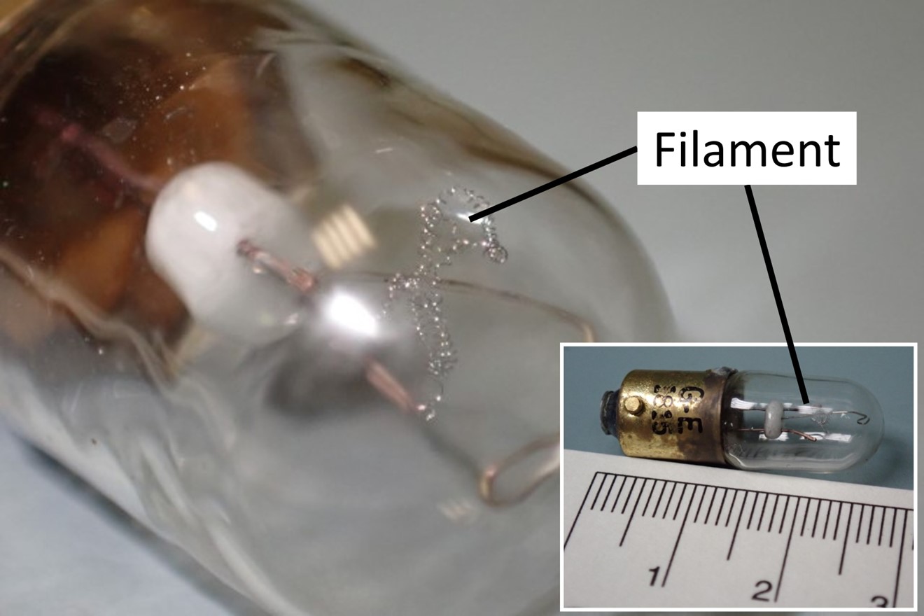 Figure 4. Enlarged view of the filament from the lightbulb removed from the occurrence aircraft’s stall warning system, with full view of the lightbulb in inset (scale reference in cm) (Source of images: TSB)